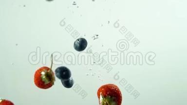 不同的美味水果在白色背景下缓慢地落入水中。 蓝莓和草莓。